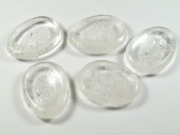 Kryształ górski szlifowany - płaski kamień. Pięć przezroczystych, gładkich kamieni leży na białym tle.