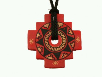 Czerwony, ozdobny wisior w kształcie krzyża na czarnym sznurku z ludowym wzorem.