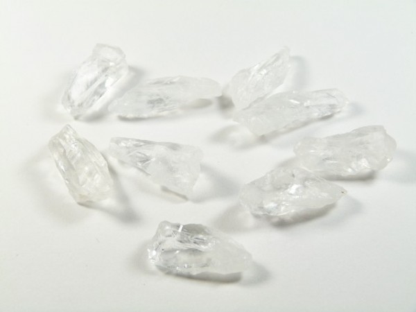 Dziewięć przezroczystych kryształków na białym tle.