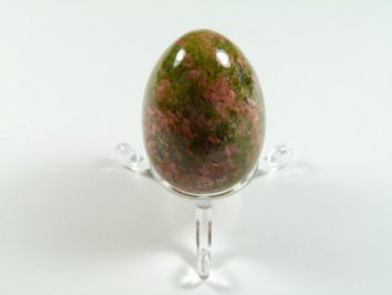 Jajko unakit szlifowany. Jajko z polerowanego różowo-zielonego kamienia na przezroczystej podstawce.