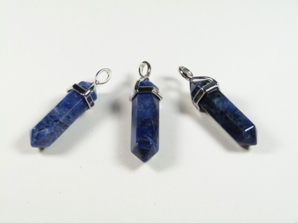 Trzy niebieskie, sześciokątne wisiorki z kamieni na białym tle.