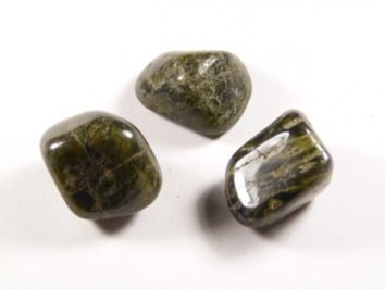 Trzy gładkie, ciemnozielone kamienie na białym tle.