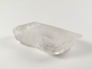 Przezroczysty kryształ kwarcu leży na białym tle.