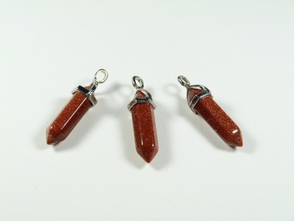 Trzy brązowe kamienie w kształcie kryształu, oprawione w srebrne zawieszki na biały tle.