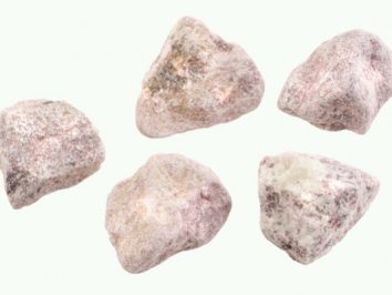 Pięć surowych, różowo-białych kamieni leży na jasnym tle.