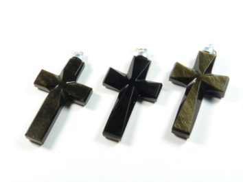 Trzy czarne krzyżyki z kamienia leżące na białym tle.