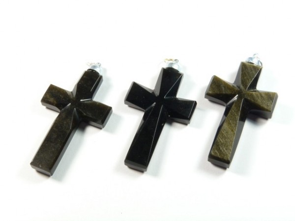 Trzy czarne krzyżyki z kamienia leżące na białym tle.