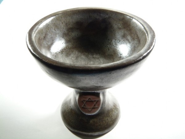 Ciemna, ceramiczna misa na nodze z wyrytym symbolem gwiazdy Dawida na podstawie.