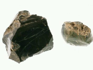 Dwa kawałki czarnego obsydianu na białym tle.