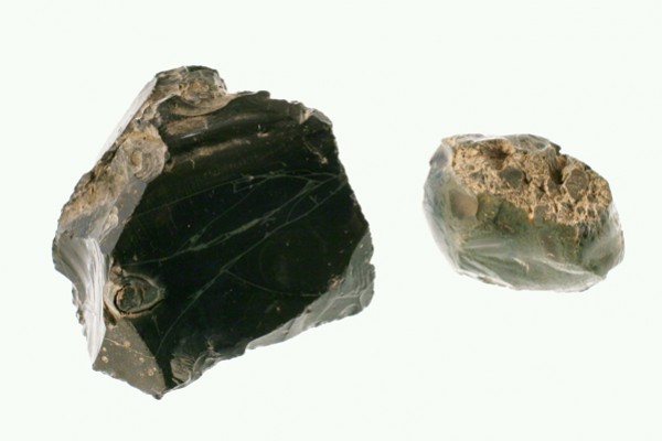 Dwa kawałki czarnego obsydianu na białym tle.