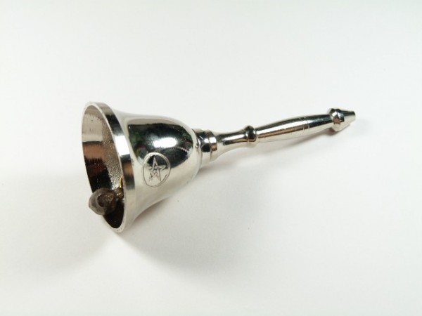 Srebrny dzwonek z wygrawerowaną gwiazdą leżący na białym tle.