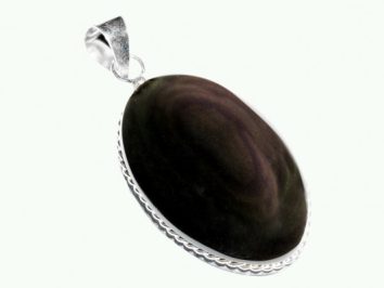 Owalny wisior z ciemnym kamieniem oprawionym w srebro na jasnym tle.