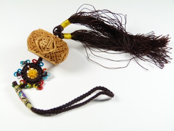 Ozdobny breloczek z plecionką, kolorowymi koralikami i brązowym chwostem na białym tle.