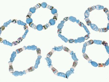 Siedem niebieskich bransoletek z koralików ułożonych w okrąg na jasnym tle.