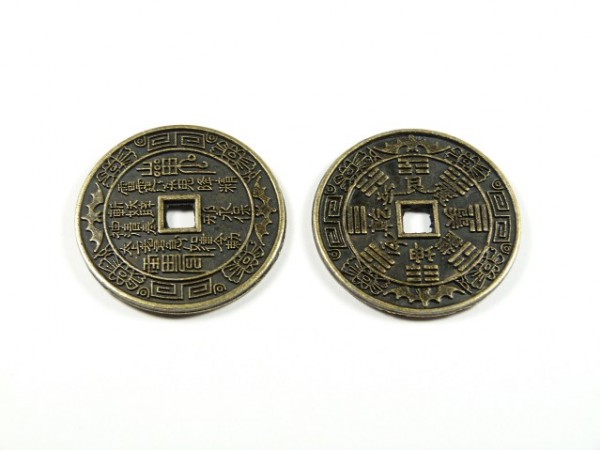 Dwa chińskie monety z kwadratowym otworem pośrodku, leżące na białym tle.