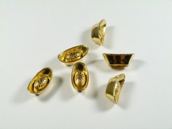 Sześć małych złotych sztabek w kształcie łódek na białym tle.