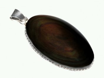 Owalny wisiorek z ciemnego kamienia oprawiony w srebrną ramkę na jasnym tle.
