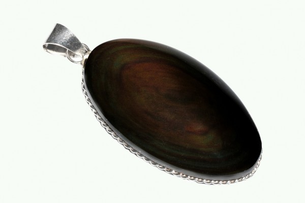 Owalny wisiorek z ciemnego kamienia oprawiony w srebrną ramkę na jasnym tle.