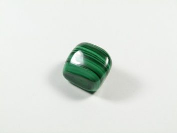 Wypolerowany zielony kamień malachit na białym tle.