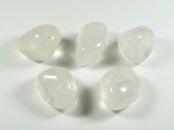 Girasol - kamień gładzony, polerowany, szlifowany i bębnowany w formie otoczaka. Pięć przezroczystych, oszlifowanych kamieni leży na białym tle.