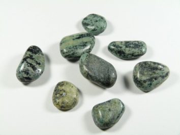 Osiem zielonych, wygładzonych kamieni leży na białym tle.