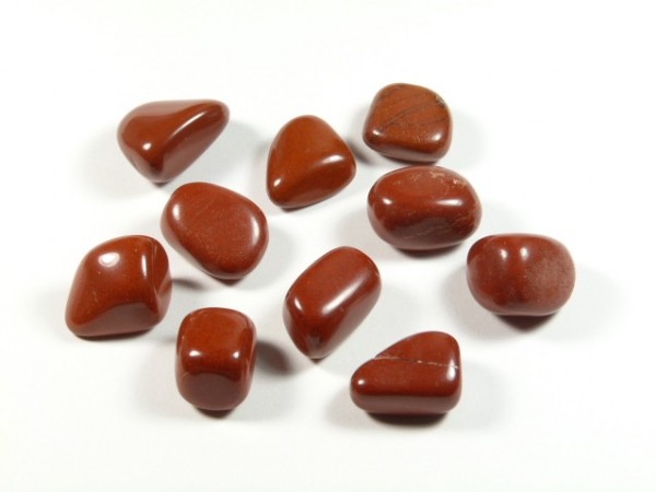 Jaspis czerwony - kamień gładzony, polerowany, szlifowany i bębnowany w formie otoczaka. Dziesięć wygładzonych, czerwonych kamieni leży na białym tle.