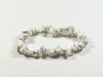 Bransoletka z białych kamieni nawleczonych na elastyczną żyłkę, na białym tle.