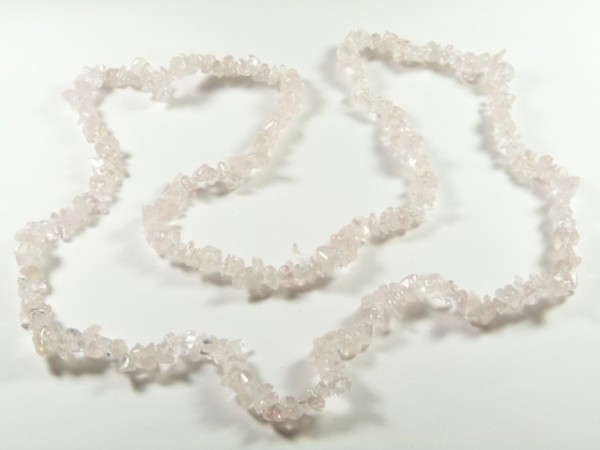 Naszyjnik z drobnych, jasnoróżowych kamieni ułożony na białym tle.