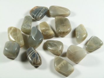 Kilka wypolerowanych kamieni księżycowych ułożonych na białym tle.