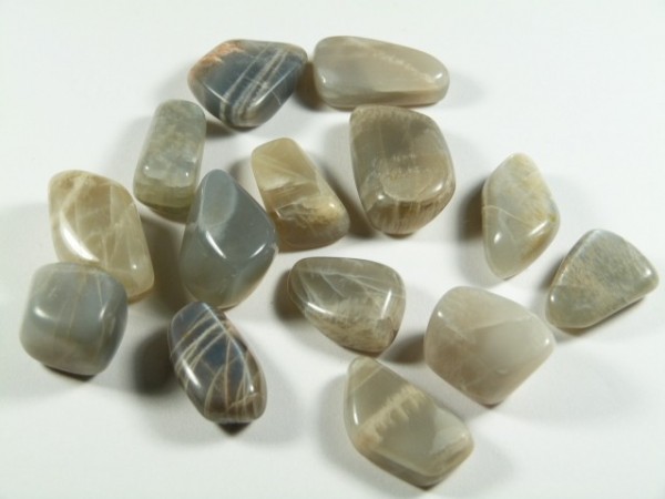 Kilka wypolerowanych kamieni księżycowych ułożonych na białym tle.