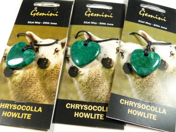 Trzy naszyjniki z zielonym sercem na czarnym sznurku, oznaczone jako Gemini, chryzokola i howlit.