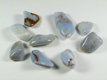 Osiem niebieskich, wypolerowanych kamieni leży na białym tle.