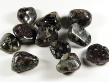 Kilka wypolerowanych, ciemnych kamieni leży na białym tle.