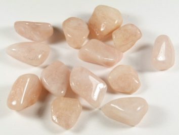 Jasnoróżowe, oszlifowane kamienie leżące na białym tle.