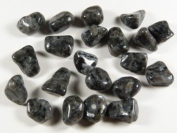 Kilka wypolerowanych, czarnych kamieni leży na białym tle.