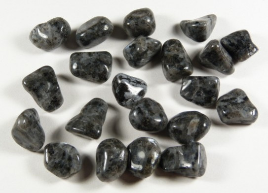 Kilka wypolerowanych, czarnych kamieni leży na białym tle.