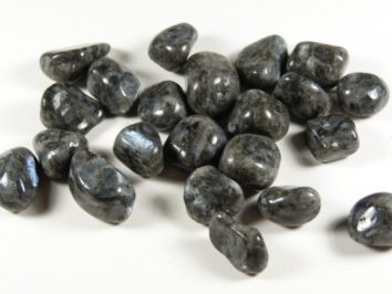 Kilka wygładzonych, ciemnoszarych kamieni leży na białym tle.