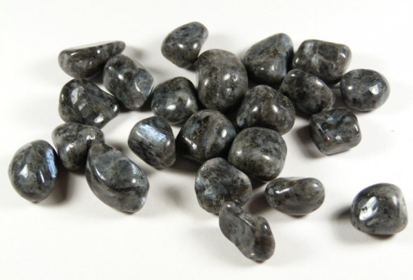 Kilka wygładzonych, ciemnoszarych kamieni leży na białym tle.