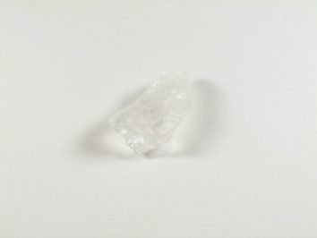 Przezroczysty kryształ soli leżący na białym tle.