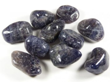 Polerowane kamienie iolitu leżące na białym tle.