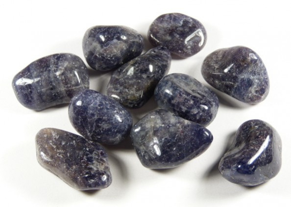 Polerowane kamienie iolitu leżące na białym tle.