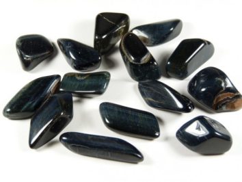 Gładkie, czarne kamienie szlachetne rozsypane na białym tle.