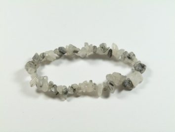 Bransoletka z nieregularnych, biało-szarych kamieni na elastycznej gumce, na białym tle.