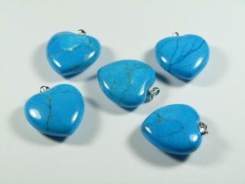 Serce/ serduszko howlit turkusowy wisiorek, szerokość 2,5 cm. Pięć niebieskich, sercowatych zawieszek z kamienia ułożonych na jasnym tle.