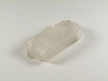 Przezroczysty kryształ kwarcu leżący na białym tle.