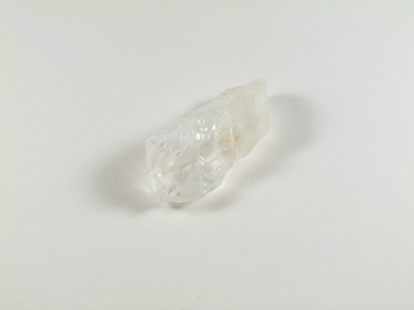 Przezroczysty kryształ kwarcu leży na białym tle.