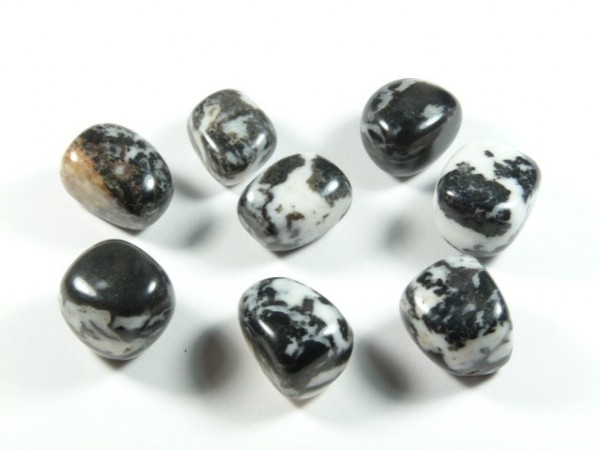 Jaspis zebra - kamień gładzony, polerowany, szlifowany i bębnowany w formie otoczaka. Osiem polerowanych kamieni zebrytu o czarno-białych wzorach na białym tle.