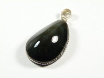 Czarny, łzawy wisiorek z kamieniem oprawionym w srebrną ramkę, na białym tle.