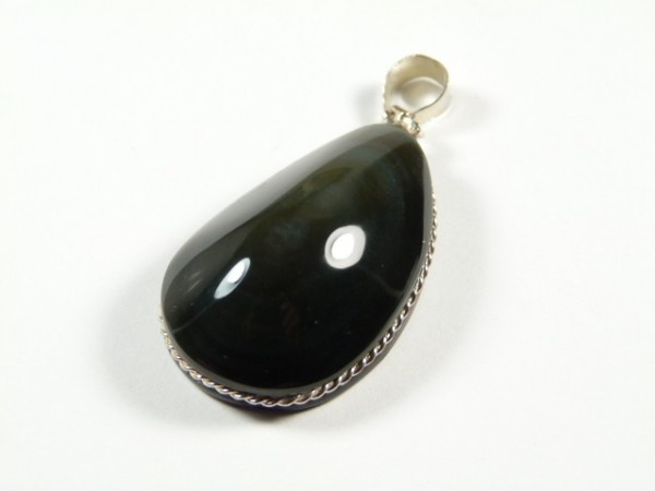 Czarny, łzawy wisiorek z kamieniem oprawionym w srebrną ramkę, na białym tle.