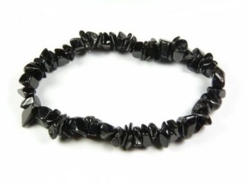 Bransoletka z czarnych, nieregularnych kamieni na elastycznej żyłce, na białym tle.